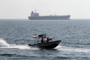 Iranian Revolutionary Guards drive a speedboat in front of an oil tanker at the port of Bandar Abbas