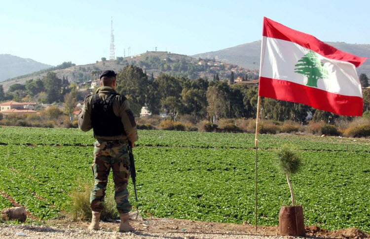 A Lebanese soldier next to the Lebanese flag