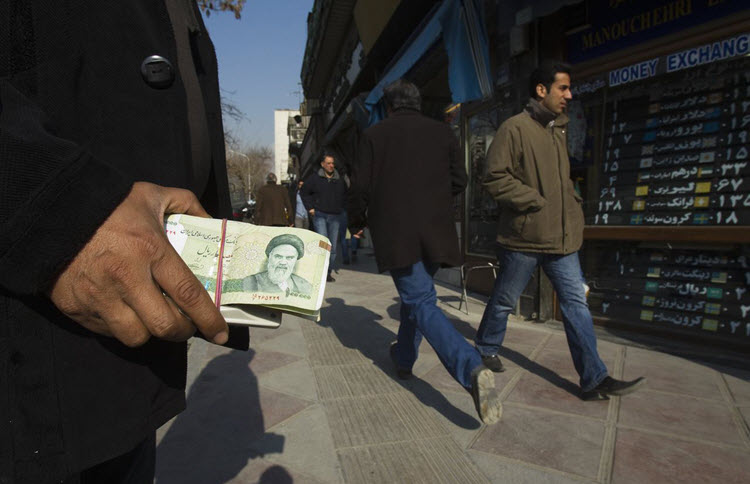 A money changer holds Iranian rial banknotes as he waits for customers in Tehran's business district