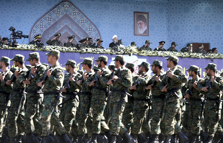 Iran's President Hassan Rouhani, top center, reviews IRGC troops marching.